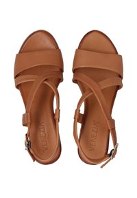 Brown leather sandals with crisscross straps, open toe, and a low heel. Features a side buckle closure and embossed logo on the insole.