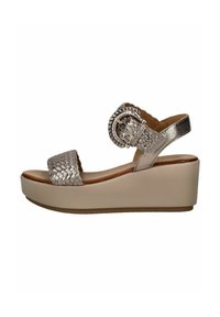 Sandalo con zeppa dalla parte superiore intrecciata in argento, punta aperta e un accento circolare. Base in beige con finitura testurizzata.