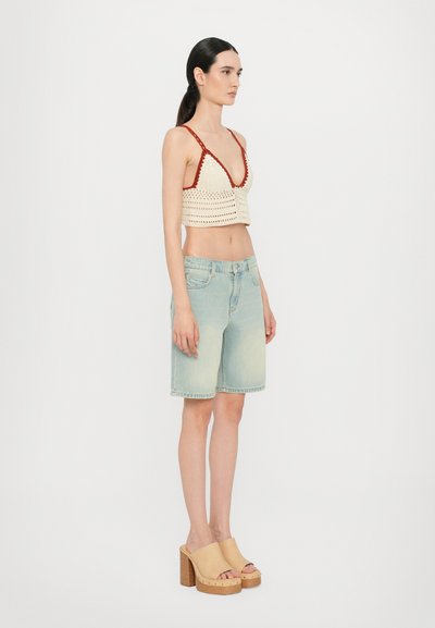 Kreemjas ja punases heegeldatud crop top, kombineeritud helesiniste denimist lühikeste pükste ja beežide platvormkingadega, millel on paks puidust konts.