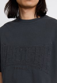 Black cotton t-shirt featuring a textured, embroidered logo "VERTERE" and "BERLIN" in a contrasting style on the front.