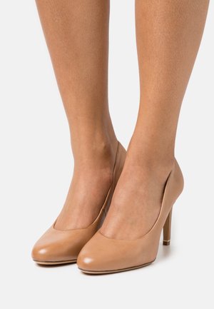 Escarpins en cuir verni beige avec un bout arrondi et un design épuré, présentant un talon aiguille effilé et des côtés minimalistes.