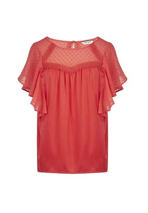Blouse rose corail avec empiècement en voile à pois et manches volantées, détail en dentelle et encolure ronde avec fermeture par bouton au dos.