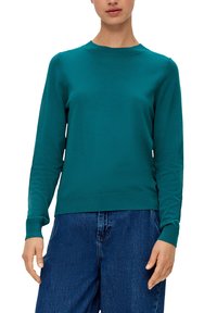 Jersey de punto en color verde azulado con mangas largas, puños acanalados y escote redondo, combinado con pantalones de mezclilla de corte holgado. Textura suave, diseño minimalista.