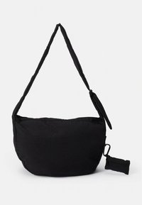 Čierna textilná taška na rameno s mäkkým, polstrovaným tvarom, nastaviteľným remienkom a vreckom na zips na jednej strane.