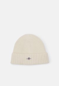 Ribbed cream knit beanie with a folded cuff, featuring a small embroidered logo on the front, made from soft fabric.