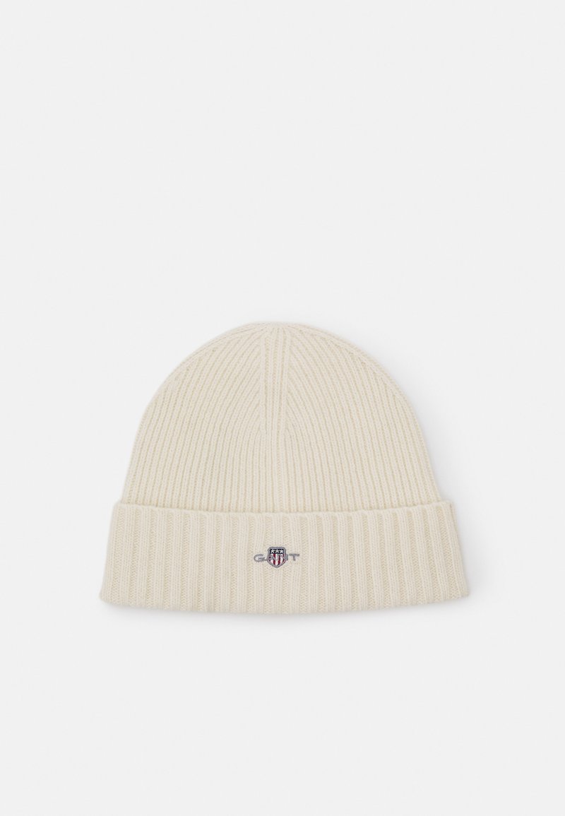 Ribbed cream knit beanie with a folded cuff, featuring a small embroidered logo on the front, made from soft fabric.
