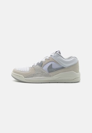 Baskets basses blanches et beiges Nike avec lacets, empiècements en daim et logo swoosh gris sur le côté, présentées sur fond blanc.