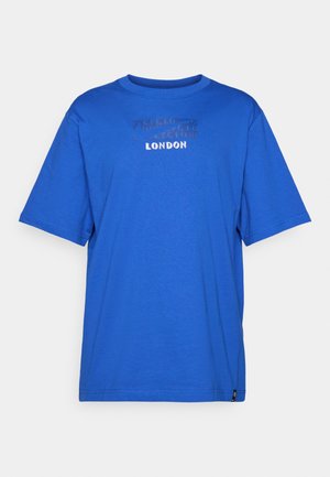 Sininen puuvillapaita, jossa on pyöreä kaula-aukko, lyhyet hihat ja teksturoitu printti, jossa lukee "LONDON" edessä. Ei kuvioita tai koristeita.