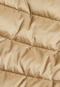 Beige Pufferjacke aus einem glatten, glänzenden Material. Besitzt gesteppte Abschnitte, die ein Muster aus sanften, abgerundeten Erhebungen erzeugen.