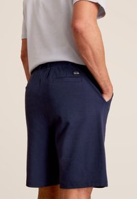 Shorts bleu marine en coton doux, avec une taille élastique, des poches latérales et un petit logo de marque sur la poche arrière.