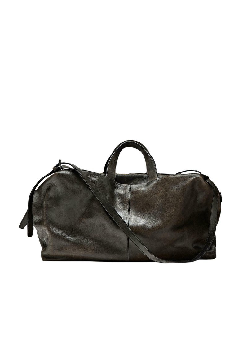 Black leather duffle bag with a smooth texture, featuring dual handles and a long shoulder strap. Rounded shape with a zippered top.