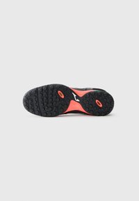 Black athletic shoe outsole with a textured surface, featuring a bright orange midsole and circular tread patterns for traction.