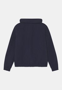 Marineblå jakke med høj krave, elastiske manchetter og talje. Glat tekstur, præsenterer et rent, minimalistisk design uden synligt hardware.