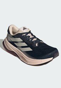 Scarpa da ginnastica nera con dettagli chiari, tomaia in rete, tre strisce riflettenti, collare imbottito e suola in gomma testurizzata.