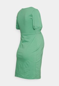 Vestido verde de manga curta em tecido jersey suave, com decote redondo, cintura justa e corte até ao joelho com uma textura lisa.