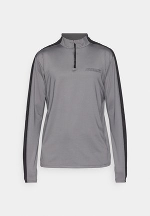Grijze sporttop met lange mouwen en een halve rits kraag, zwarte accenten aan de zijkanten en het "HUMMEL" logo op de borst. Glad, lichtgewicht materiaal.