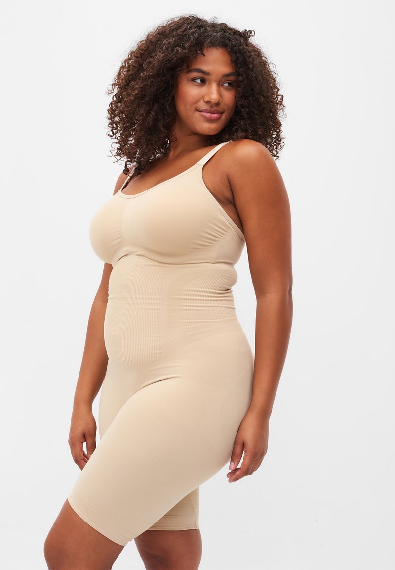 Beige shapewear bodysuit with adjustable straps, smoothing design, knee-length fit, and textured panel details for shaping.
