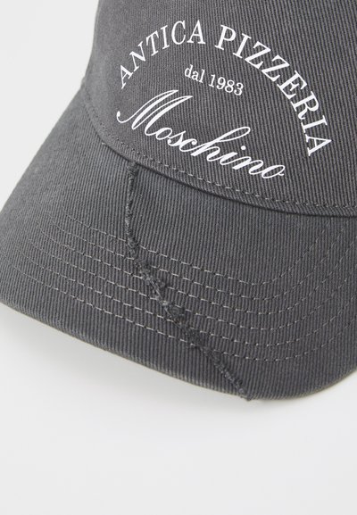 Casquette noire en tissu texturé, ornée d'un texte brodé blanc : "ANTICA PIZZERIA dal 1983 Moschino." Comprend des détails de couture visibles.