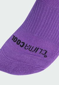 Lila socka i ribbat tyg; har svarta texten "Cool" på fotdelen. Slät textur med en tät passform.