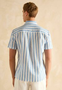 Heled varrukatega särg, millel on helesinised ja valged vertikaalsed triibud, krae, taga voldik ning kaks nupukest kaelaaugu lähedal.