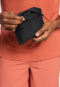 Schwarze, leichte Tasche mit Reißverschluss, in einer Hand gehalten. Hergestellt aus weichem Stoff, mit einem kompakten Design für einfache Tragbarkeit.