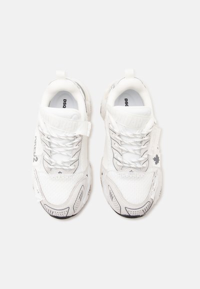Paire de baskets blanches avec des accents gris, lacets à l'avant et sangles de marque, vues de dessus sur un fond clair.