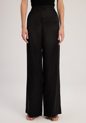 Zwarte, wijde broek met een hoge tailleband. Gemaakt van een soepele, lichte stof en heeft een subtiele textuur.