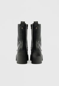 Μαύρες δερμάτινες μπότες μέχρι τον αστράγαλο με χοντρό τακούνι, που διαθέτουν φερμουάρ στο πλάι, λογότυπο στην φτέρνα και λεία υφή.