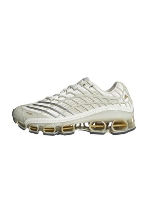 Zapatilla deportiva blanca y beige con parte superior de malla, superposición texturizada, cinco cámaras de aire visibles en la suela y cierre con cordones.