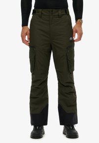 Cargo ski- of sneeuwbroek in donker olijfgroen, gemaakt van waterdicht materiaal. Voorzien van zakken, ritsen en een contrasterend zwart paneel aan de zoom.