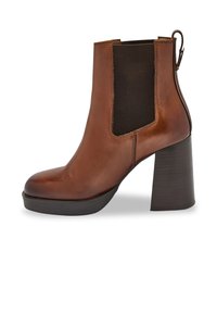 Botín de cuero marrón hasta el tobillo con un tacón grueso, paneles laterales elásticos y un detalle de lazo en la parte trasera. Acabado suave y diseño de punta redonda.