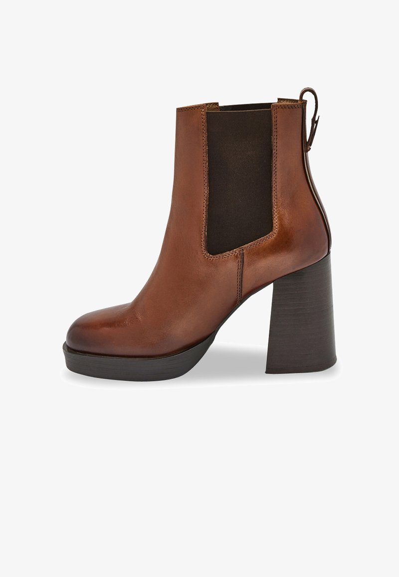 Botín de cuero marrón hasta el tobillo con un tacón grueso, paneles laterales elásticos y un detalle de lazo en la parte trasera. Acabado suave y diseño de punta redonda.