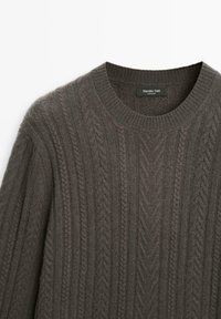Dark gray knit sweater featuring a cable pattern and a round neckline. The fabric texture appears soft, with ribbed cuffs and hem.