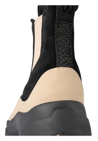 Czarno-beżowe botki sięgające kostki z zamszową i gładką cholewką, teksturowanymi plecionkami oraz solidną czarną gumową podeszwą.