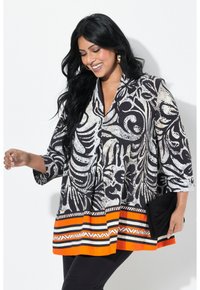 Zwart-wit gestreepte tuniek met een V-hals, driekwart mouwen en een oranje gestreepte zoom. Draagt met zwarte broeken en een zwarte clutch.