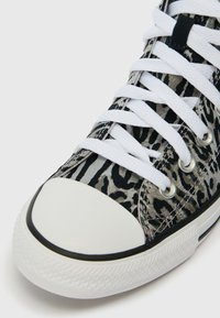 Vysoké tenisky s bielym gumovým špičkou, bielymi šnúrkami a vrchnou časťou z čierno-sivého zvieracieho vzoru.