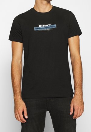 T-shirt en coton noir avec un logo "DIESEL" central agrémenté d'accents en denim. Manches courtes et col rond. Style simple et décontracté.