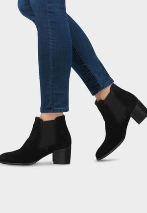 Botines de ante negros con paneles laterales elásticos y tacón cuadrado. Textura suave con costuras detalladas a lo largo de las costuras.