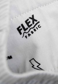 Etiqueta de tela blanca con "FLEX" en texto negro en negrita, acompañada por "Fabrics" en una fuente más pequeña. Incluye un gráfico de rayo.