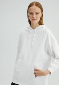 Biela mikina s kapucňou, s klokankovým vreckom, raglánovými rukávmi a nastaviteľnými šnúrkami. Mäkká tkanina a minimalistický dizajn.