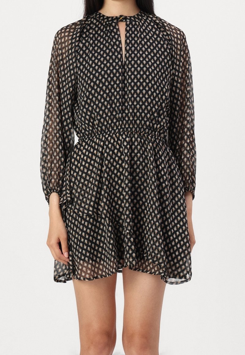 Robe noire transparente avec des manches longues, un col rond comportant une ouverture en clé, une taille cintrée et des motifs floraux dorés sur l'ensemble.