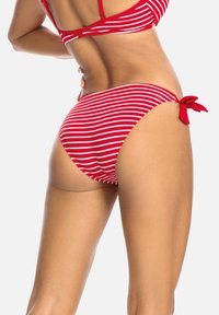 Czerwony bikini w białe poziome paski. Dolna część ma akcent w postaci węzła po prawej stronie oraz gładką, elastyczną teksturę.