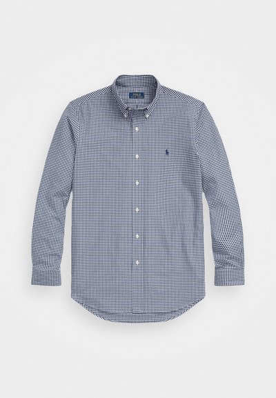 Navy and white checkered long-sleeve shirt with button-down collar, rounded hem, and embroidered logo on left chest. Cotton material.