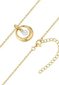 Kuldne kaelakee, millel on ümmargune ripats, kus on pärl ja ümbritsevad selged kristallid. Sisaldab homaarikinnitust ja reguleeritavat kett.