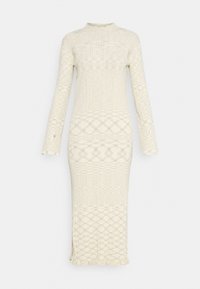 Longue robe en maille crème avec un motif discret en losanges, manches longues, col montant et petit détail volanté à l'ourlet sur un fond uni.