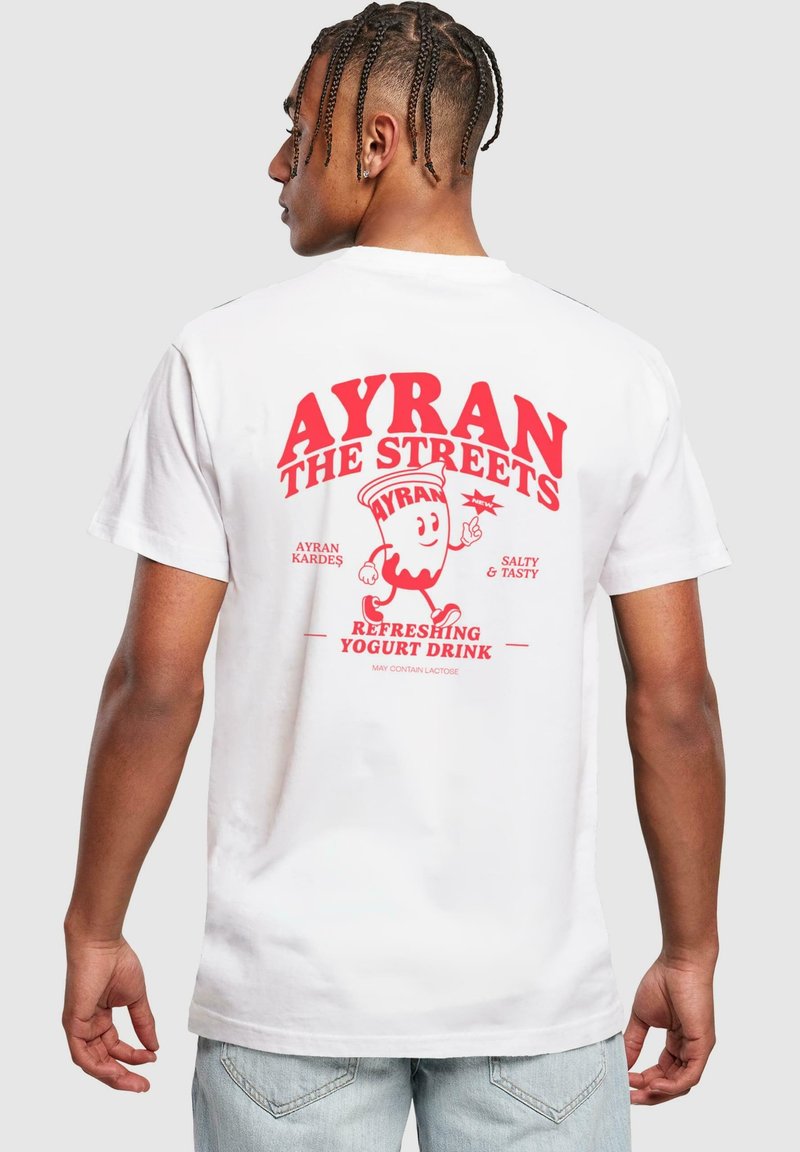 T-shirt en coton blanc avec un texte graphique rouge au dos : "AYRAN THE STREETS", accompagné d'un personnage joyeux de boisson au yaourt et de détails.