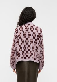 Μωβ πλεκτό πουλόβερ με σχέδιο πατουσίτσας σε σκούρο βουργουνδί, με cropped σχέδιο και χαλαρή εφαρμογή. Μαλακή υφή και πέφτουν ώμοι.