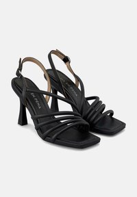 Schwarze High Heels Sandalen mit quadratischer Zehenform, mehreren schlanken Riemen und Slingback-Design. Hergestellt aus glattem synthetischen Material.