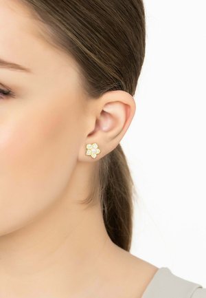 Gold flower-shaped stud earring with a central pearl and rhinestone accents. Worn on a model's ear against a neutral background.