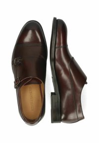 Bruine leren dubbel-monk schoenen met een gepolijste afwerking, vierkante neus en een zwarte rubberen zool. Voorzien van metalen gespen en contrasterende stiksels.